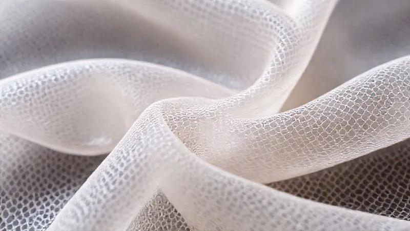 A close-up, photorealistic image of a highly flexible, intricately woven 3D printed fabric made from a translucent, soft TPU material. The fabric is gently folded, showcasing its fluid drape and elasticity. Cinematic lighting highlights the delicate texture and subtle sheen, with a shallow depth of field. Professional photography, 8K hyper-detailed, shot on a high-end DSLR, emphasizing innovation in textile materials.