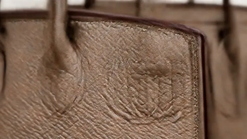 A macro shot, photorealistic, professional photography, 8K, cinematic lighting, sharp focus on the saddle stitching along the edge of a vintage Hermès Birkin flap. The stitches are slightly angled and perfectly even, showcasing meticulous hand-craftsmanship. Depth of field blurs the background, emphasizing the intricate detail. Shot on a high-end DSLR, hyper-detailed.