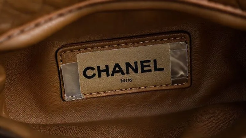A close-up, photorealistic shot of a vintage Chanel flap bag's interior, showing a partially worn but visible serial number sticker with a clear protective tape. Cinematic lighting highlights the texture of the leather lining and the precise stitching, 8K, professional photography, sharp focus, depth of field.
